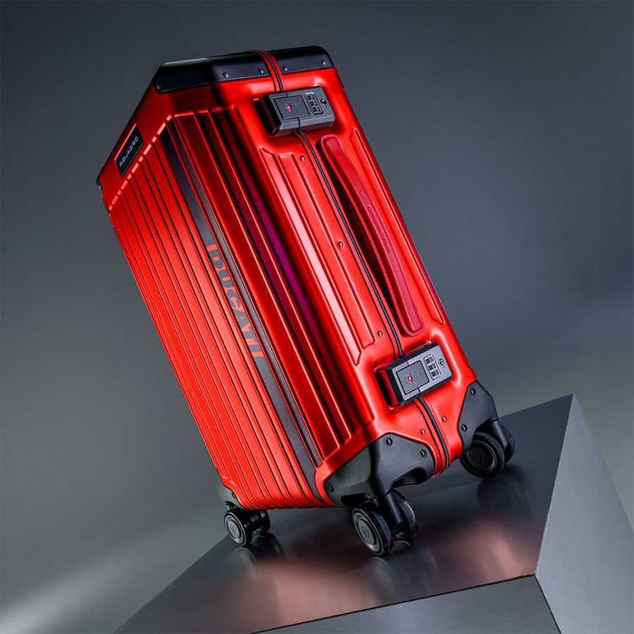 Red Ducati-branded hard-shell luggage with four wheels and built-in combination locks, positioned on a metallic platform against a grey background.
